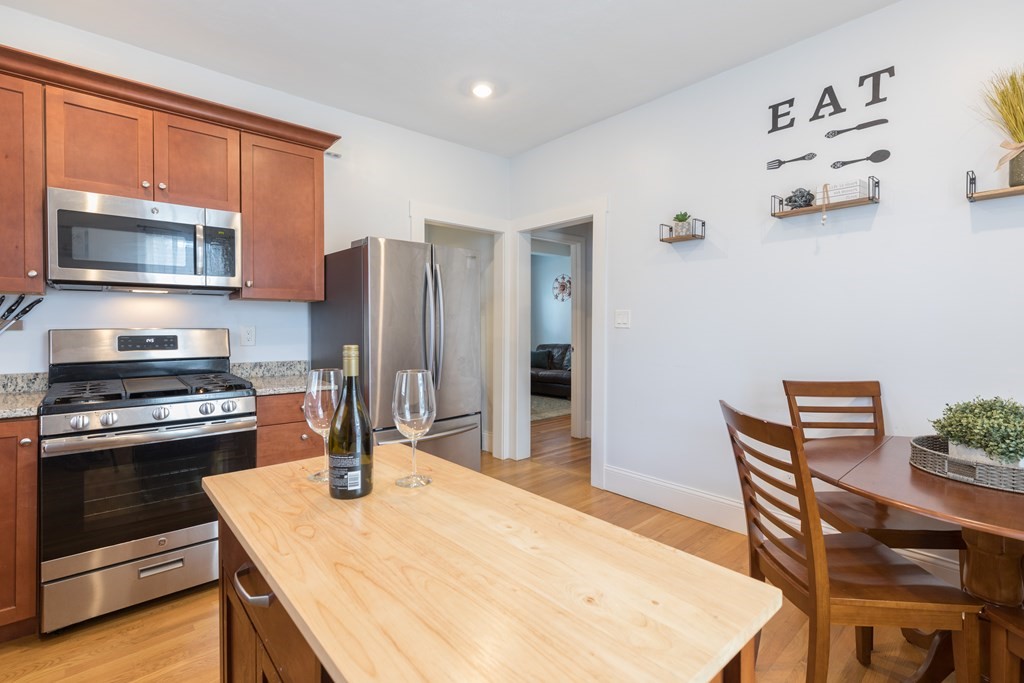 4 Cross Street, Unit 1 Malden, MA 02148 - Photo 2 of 17 a kitchen with a stove a refrigerator and a dining table