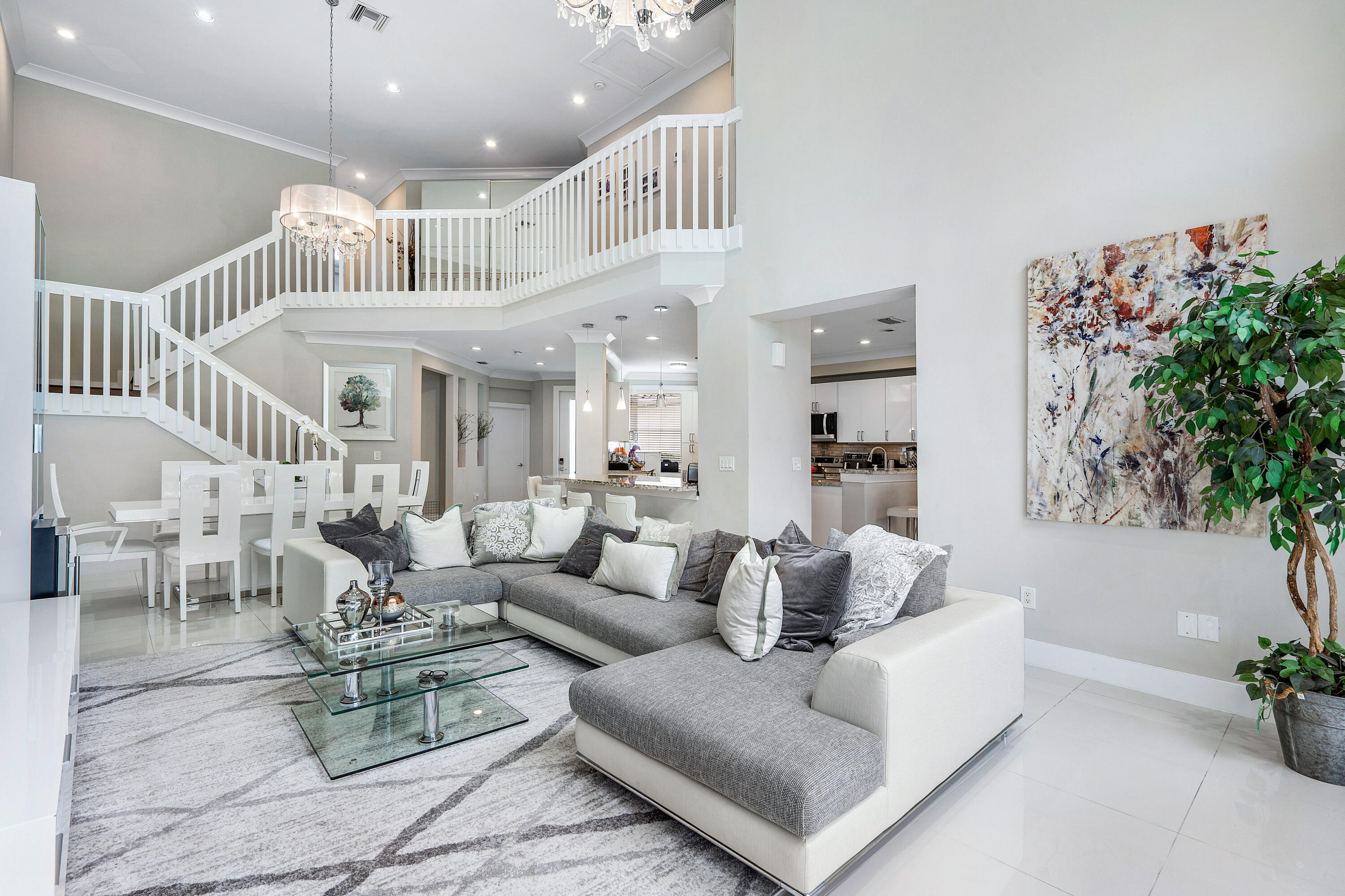 a living room with furniture kitchen view and a chandelier