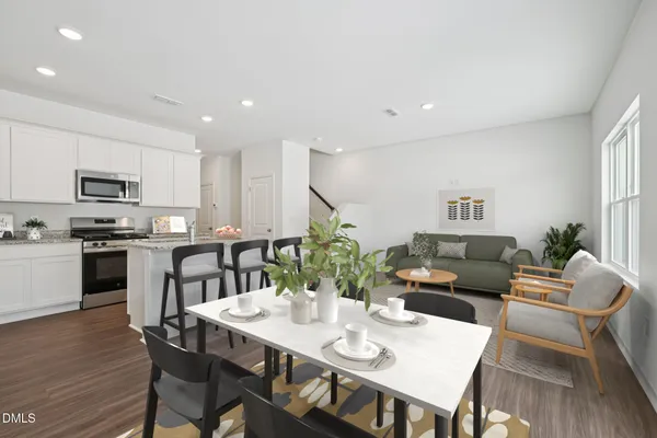 a living room with furniture kitchen view and a wooden floor