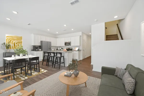 a kitchen with kitchen island a dining table chairs cabinets and wooden floor