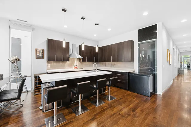 a kitchen with stainless steel appliances granite countertop a refrigerator a stove a sink a dining table and chairs with wooden floor