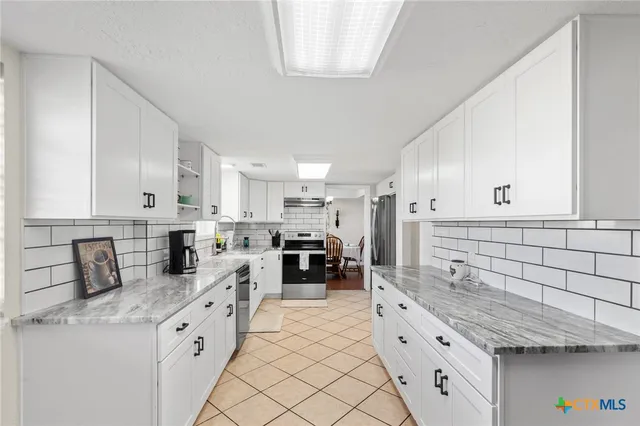 a kitchen with stainless steel appliances kitchen island granite countertop a stove sink and cabinets