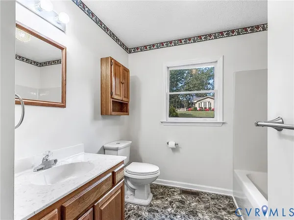 a bathroom with a granite countertop sink mirror vanity and toilet
