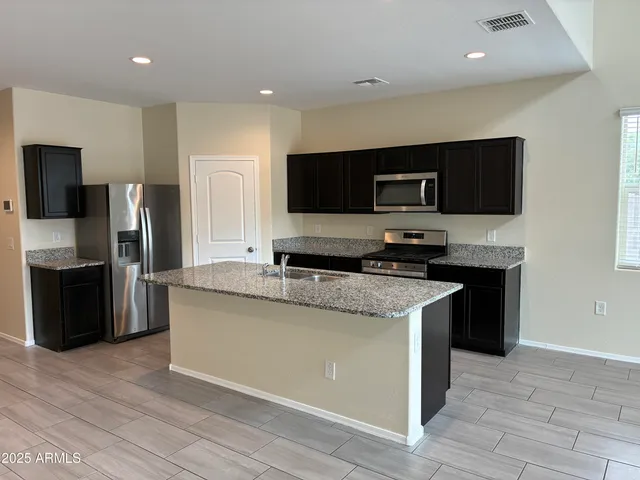 a kitchen with stainless steel appliances granite countertop a stove a sink and a refrigerator
