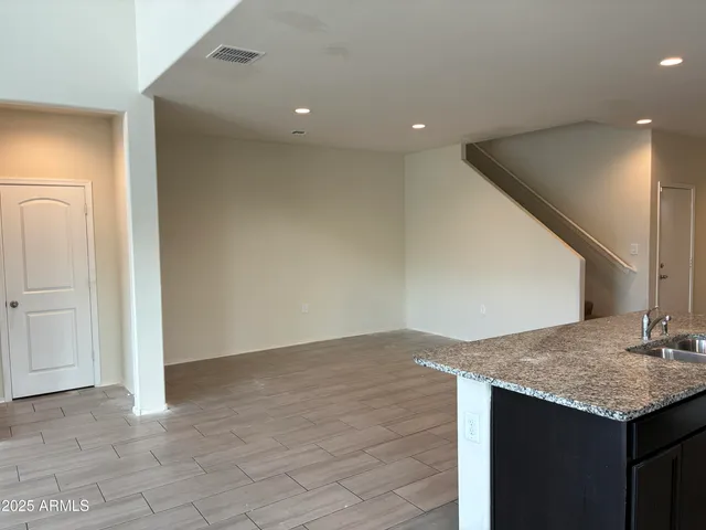 an empty room with kitchen island sink and hallway