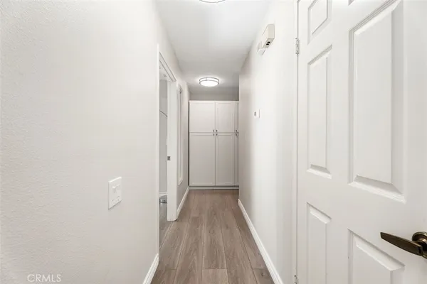 a view of a hallway with wooden floor and a bathroom