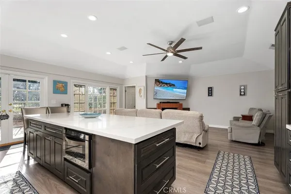 a living room with stainless steel appliances kitchen island granite countertop a stove a sink a dining table and chairs with wooden floor