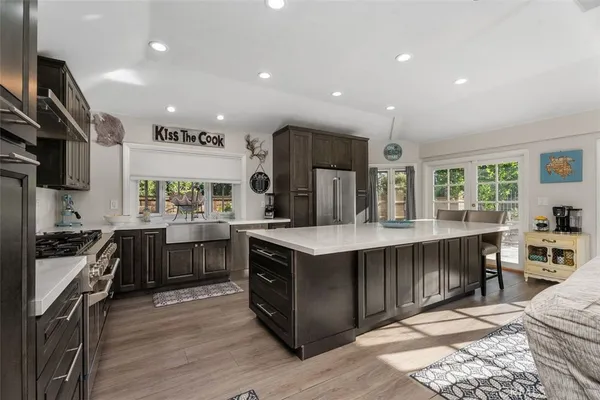 a kitchen with kitchen island granite countertop a stove top oven a sink dishwasher a dining table and chairs with wooden floor