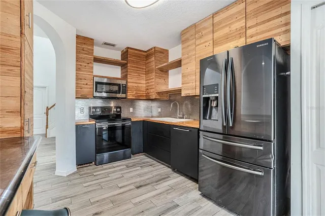 a kitchen with a refrigerator stainless steel appliances wooden floor and cabinets