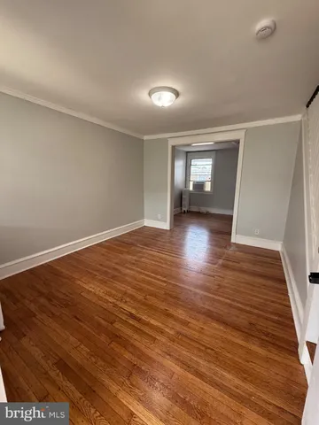 a view of empty room with wooden floor and window