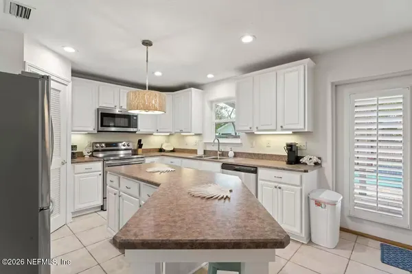 a kitchen with stainless steel appliances granite countertop a stove top oven a sink dishwasher a refrigerator and cabinets with wooden floor