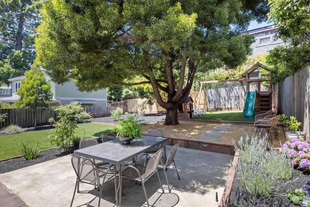 a patio with table and chairs plants and trees