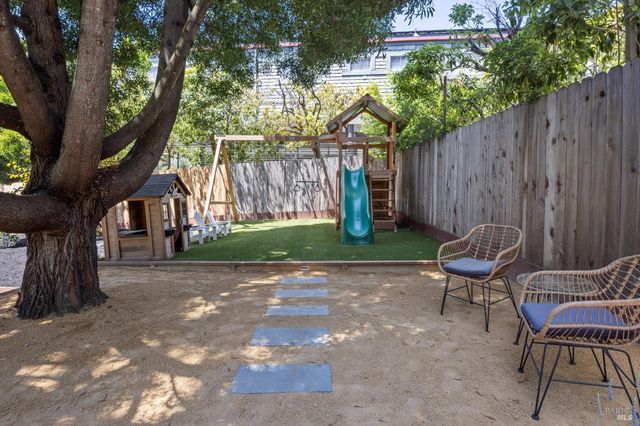 a view of a backyard with chairs potted plants and a large tree