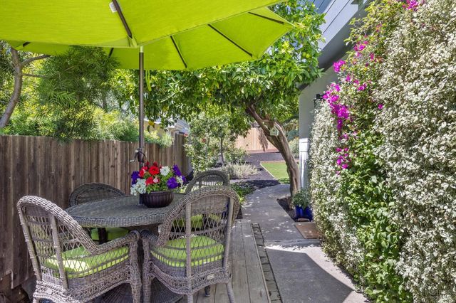 a backyard of a house with table and chairs under an umbrella