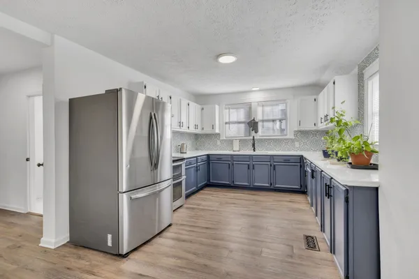 a kitchen with stainless steel appliances a refrigerator and a wooden floor