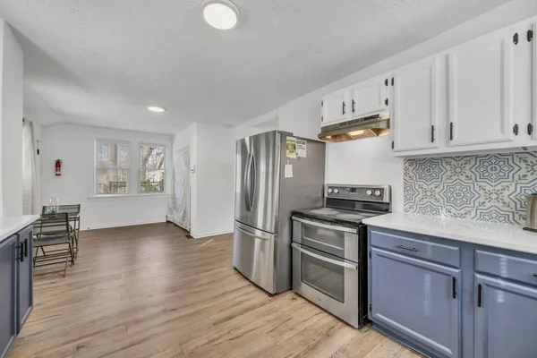 a kitchen with granite countertop a refrigerator stove and wooden cabinets