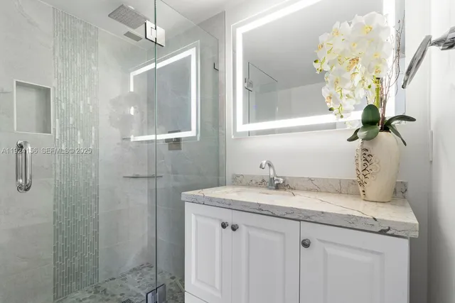 a bathroom with a granite countertop shower sink vanity and mirror