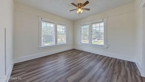 a view of an empty room with wooden floor and window