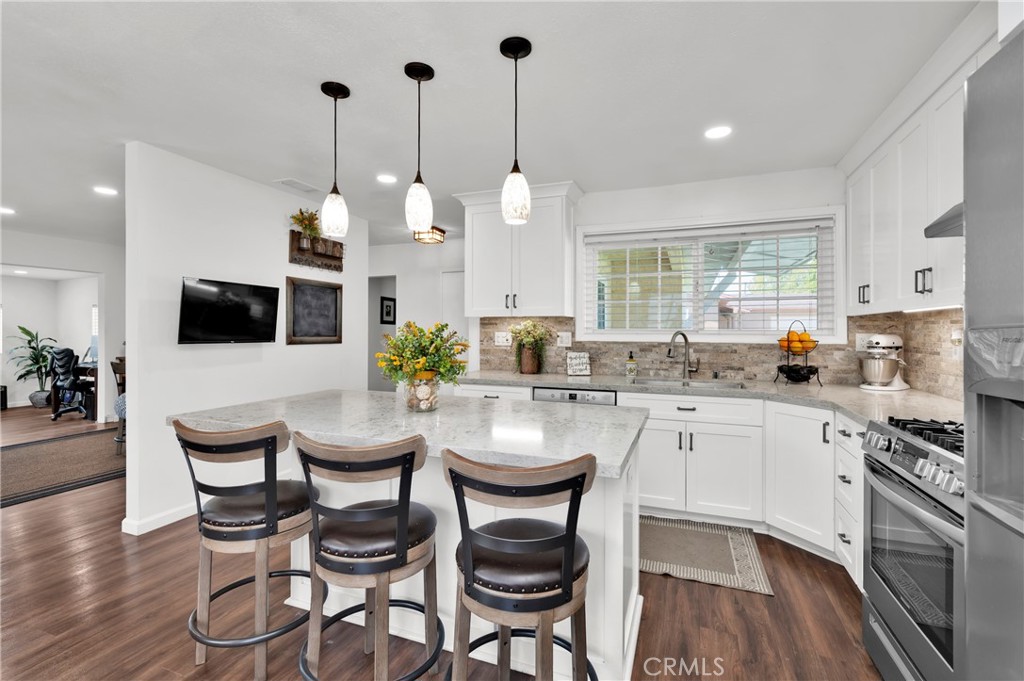 a kitchen with stainless steel appliances a dining table chairs and sink