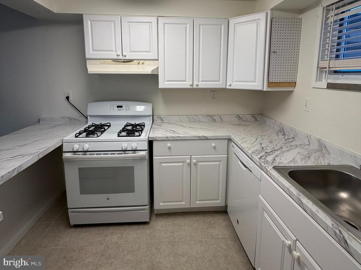 5485 Harpers Farm Road, Unit L6 Columbia, MD 21044 - Photo 4 of 20 a kitchen with granite countertop white cabinets and white stainless steel appliances