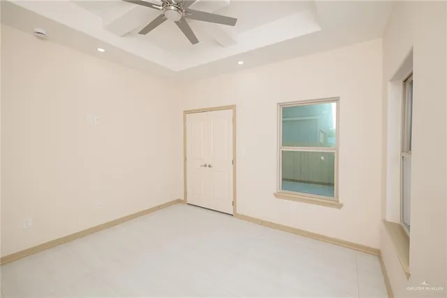 an empty room with a ceiling fan and windows
