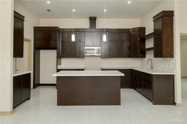 a large kitchen with stainless steel appliances a sink and a stove top oven