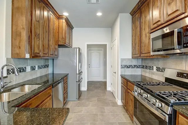 a kitchen with stainless steel appliances granite countertop a refrigerator and a sink