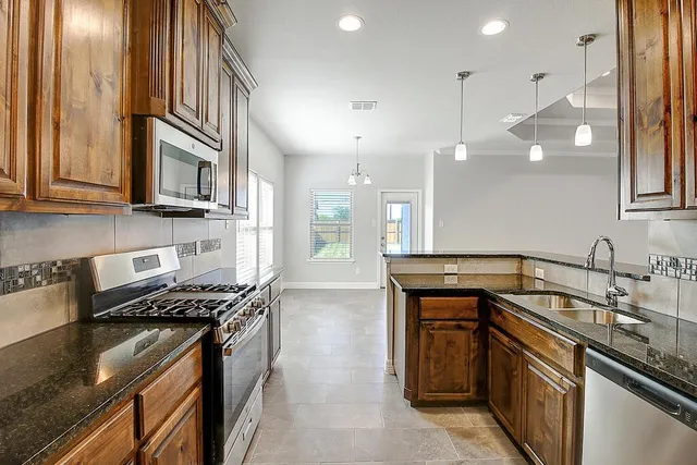 a kitchen with granite countertop a sink a stove and wooden cabinets