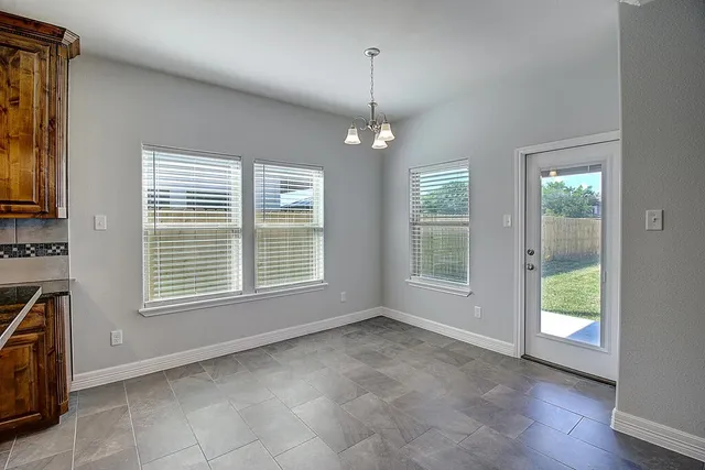 a kitchen with stainless steel appliances granite countertop a stove a sink a refrigerator white cabinets and a dining table