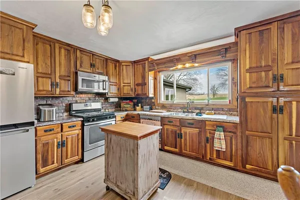 a kitchen with stainless steel appliances granite countertop a stove top oven a sink dishwasher a refrigerator and cabinets with wooden floor