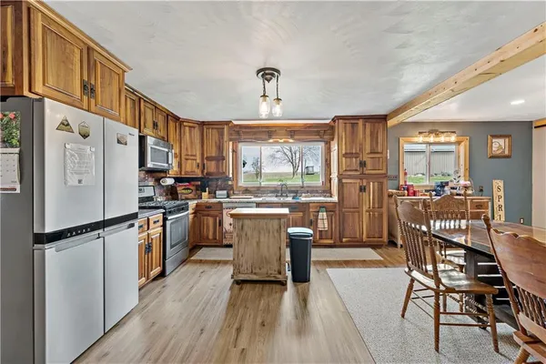 a kitchen with a refrigerator a stove top oven a sink dishwasher a dining table and chairs with wooden floor