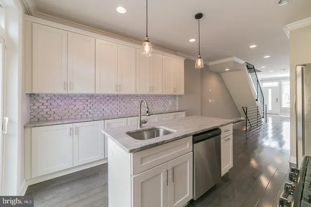 a kitchen that has a sink a microwave oven a stove and white cabinets with wooden floor