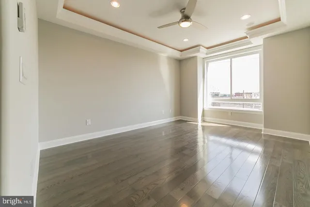 an empty room with wooden floor fan and windows