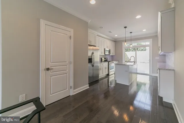 a view of a kitchen with refrigerator and wooden floor