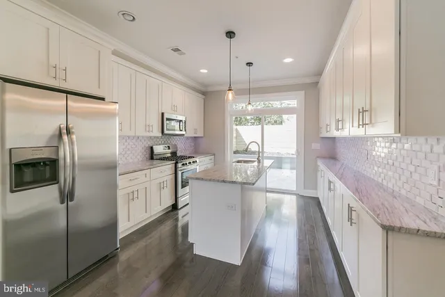 a kitchen with stainless steel appliances granite countertop a refrigerator a sink dishwasher a stove and white countertops with wooden floor