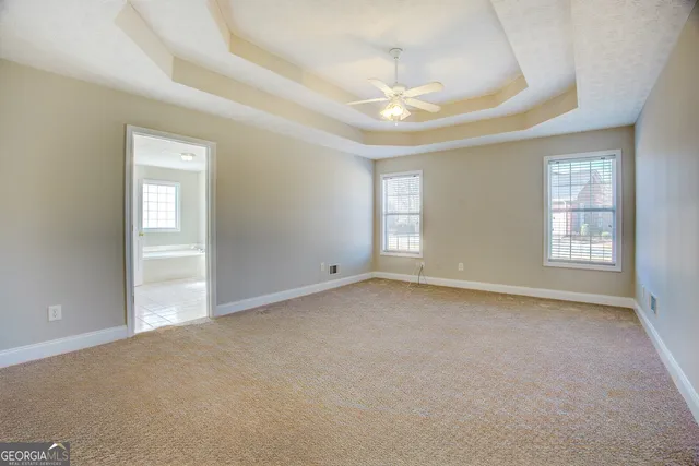 an empty room with windows and chandelier fan