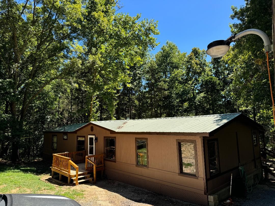 1019 Katy Lane Bethpage, TN 37022 - Photo 2 of 17 a view of a patio with couches table and chairs under an umbrella with large trees