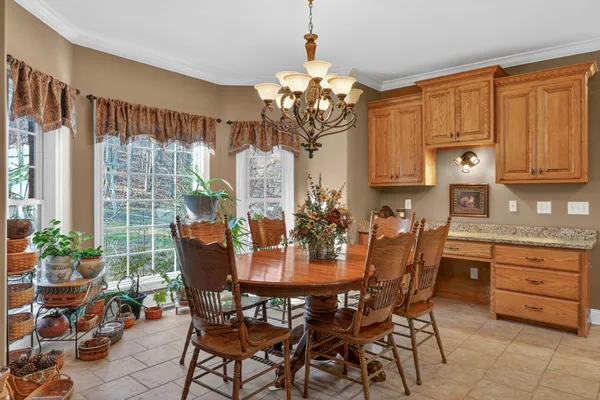 a dining room filled chandelier and wooden furniture