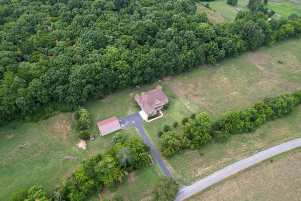an aerial view of residential house with outdoor space and trees all around