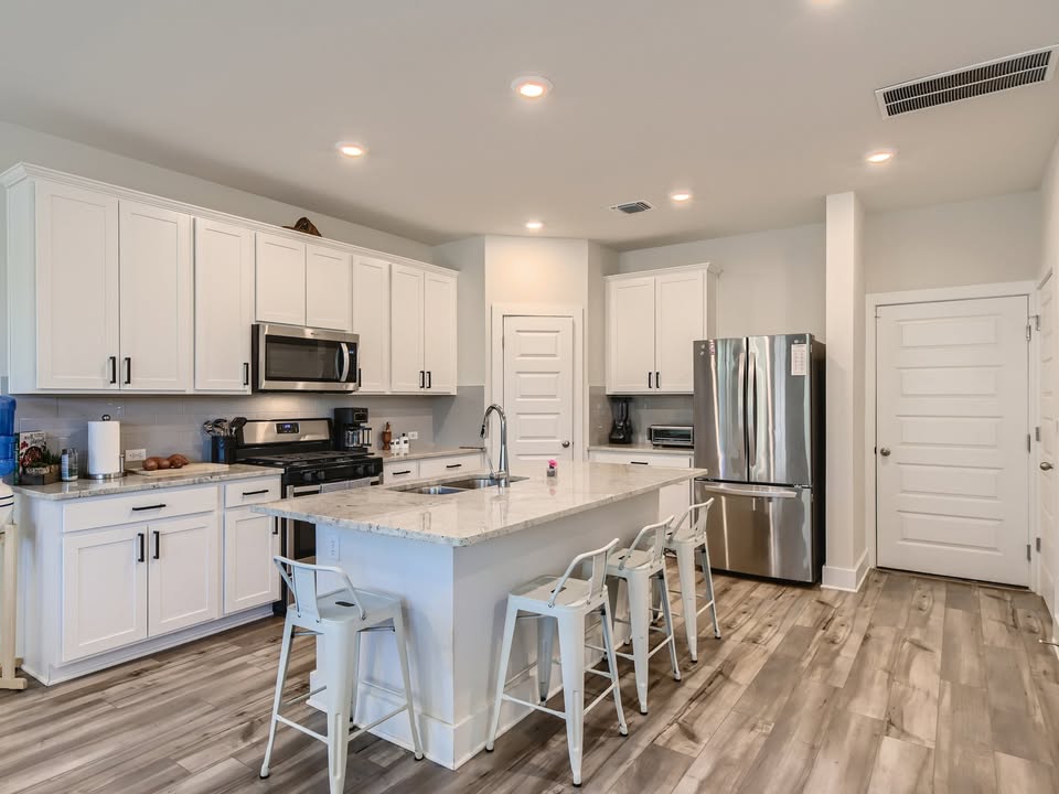 7103 Terrazzo Cottage Lane, Unit 33 Austin, TX 78744 - Photo 4 of 14 a kitchen with appliances a sink cabinets and wooden floor