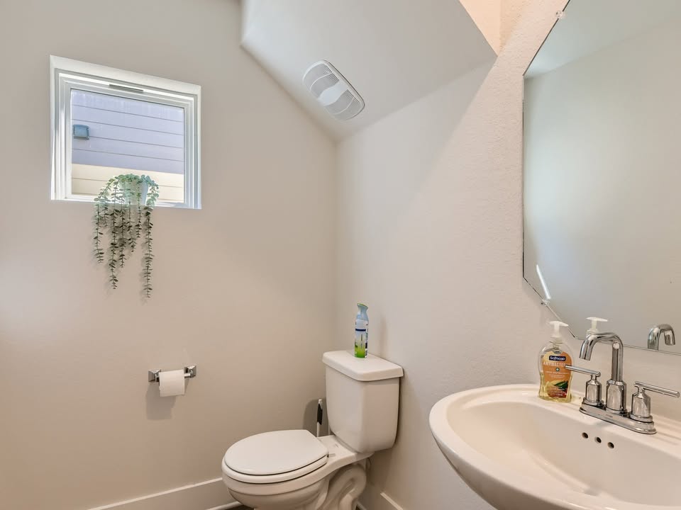7103 Terrazzo Cottage Lane, Unit 33 Austin, TX 78744 - Photo 6 of 14 a bathroom with a toilet a sink and a mirror