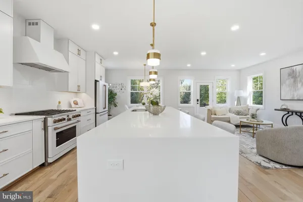 a kitchen with stainless steel appliances kitchen island a large counter top a sink a stove and a wooden floors
