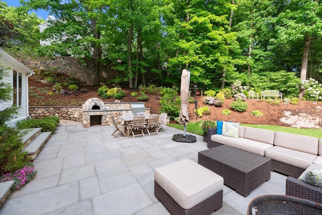 77 Royalston Road Wellesley, MA 02481 - Photo 2 of 30 a view of a patio with couches and chairs under an umbrella with large trees
