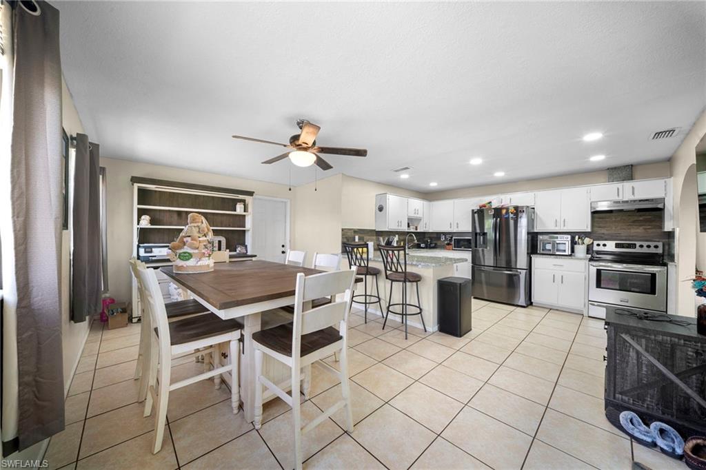 7289 Barragan Road Fort Myers, FL 33967 - Photo 10 of 18 Open-concept kitchen featuring white cabinetry, stainless steel appliances, a center island with bar seating, and tile flooring