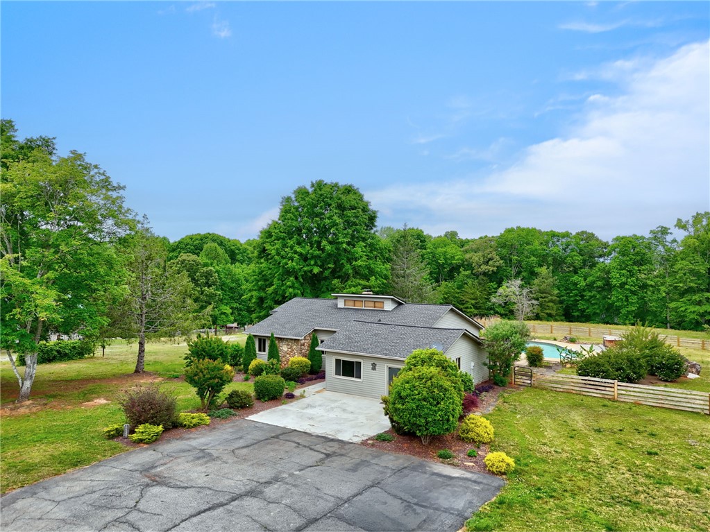 433 Latham Road Easley, SC 29640 - Photo 37 of 50 A well-maintained residence with mature landscaping and a private pool, set against a backdrop of verdant woodlands.