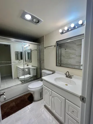 a bathroom with a sink a toilet a mirror and shower