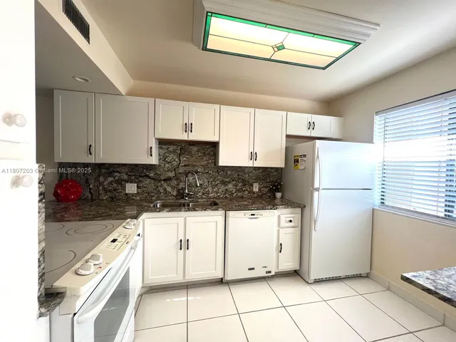 a kitchen with white cabinets and white appliances