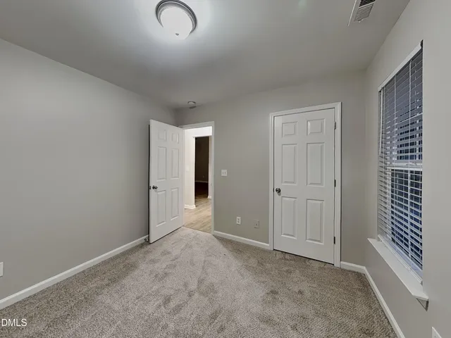 a view of an empty room with window and closet area