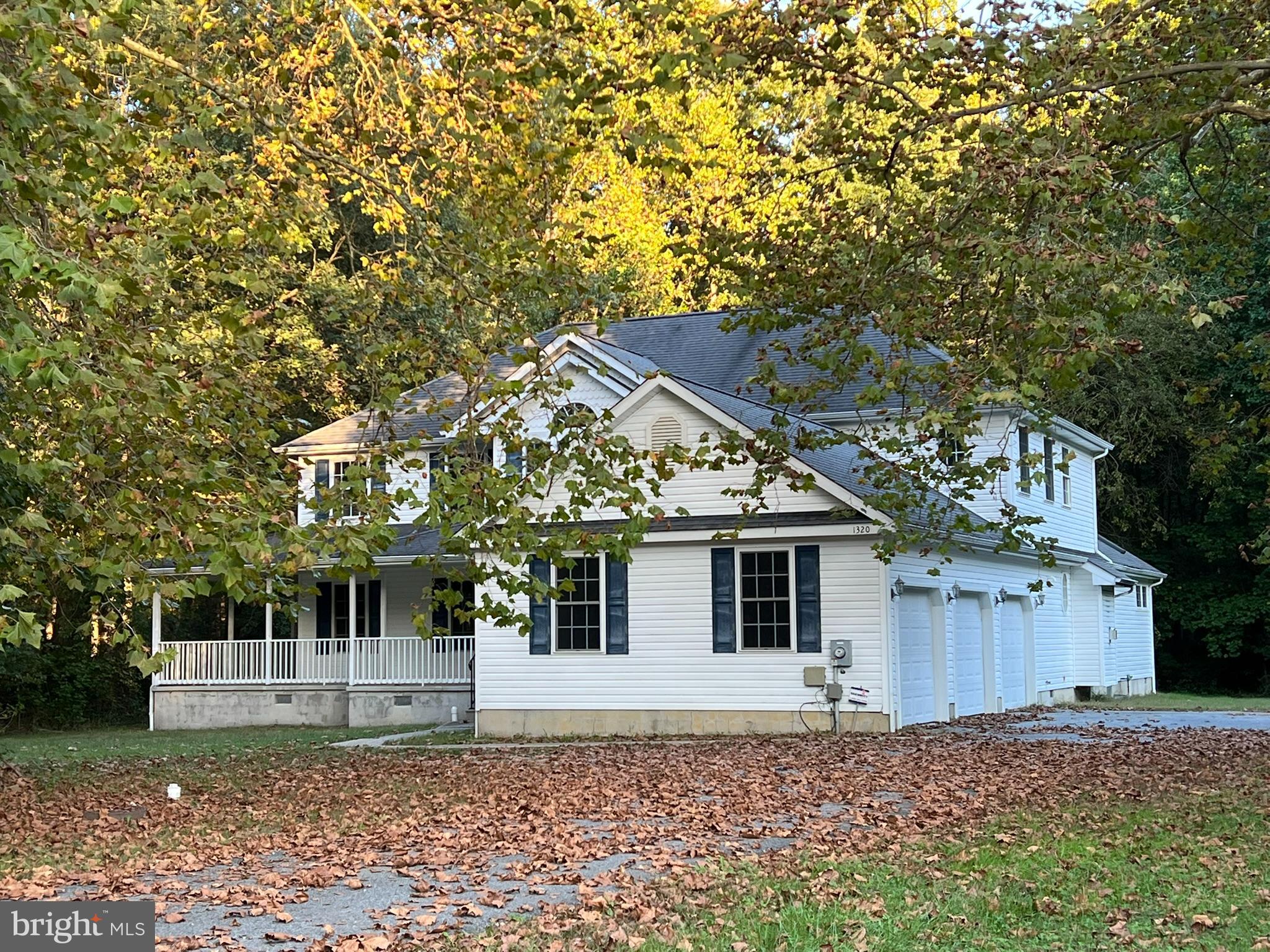 a view of a white house with a large tree and wooden fence