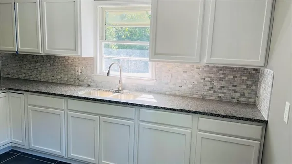 a kitchen with granite countertop white cabinets and a sink